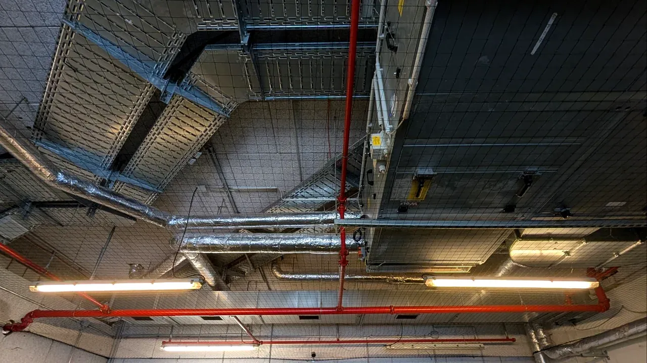 Netzfeld unter der Tiefgaragendecke, um Kabeltrassen, Lüftungsrohre und Sprinklerleitung herum eingefasst